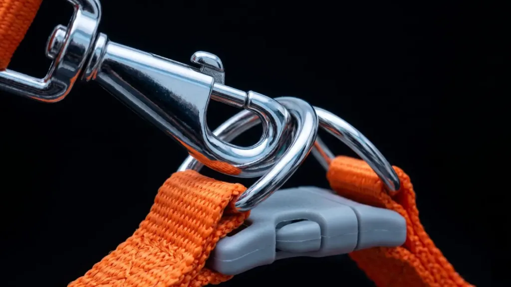A high-resolution, detailed studio shot of matte-finish, aerospace-grade aluminum alloy hardware on a dog harness, contrasting with a vibrant nylon strap, exuding a lightweight and premium tech feel.